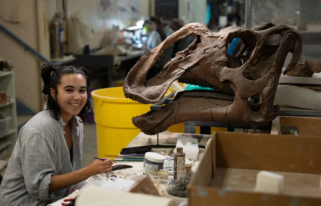 A woman working in front of dinosaur head